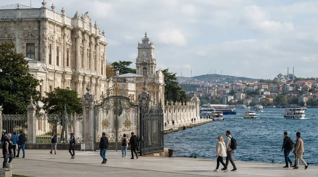 die kunstvolle Uferfassade des Dolmabahçe-Palasts bei Tag, mit hellem Stein, geschnitzten Details und dem Bosporus direkt hinter den Toren