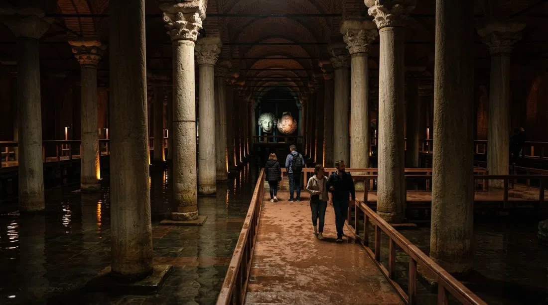 interno della Cisterna Basilica con file di colonne di pietra riflesse nell'acqua bassa e le teste di Medusa illuminate drammaticamente in lontananza